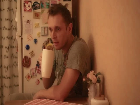 A man in the kitchen drinks tea and thinks about something Stock Footage 82185099