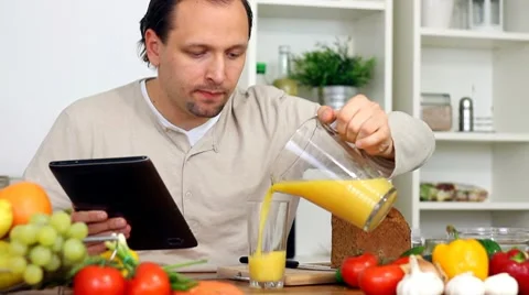 Man in kitchen with electronic tablet drink juice Stock Footage 8983587