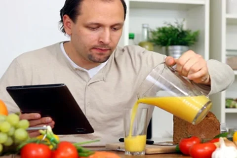 Man in kitchen with electronic tablet drink juice Stock Footage 8983590