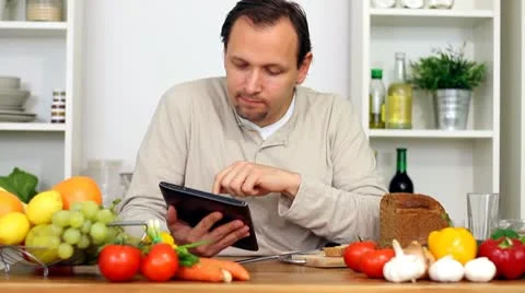 Man in kitchen with electronic tablet eat breakfast Stock Footage 8983558