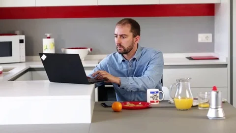 A man in the kitchen having breakfast with his laptop. Stock Footage 116346844
