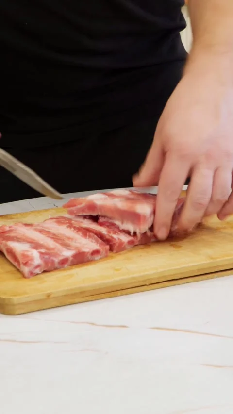 A man in the kitchen of the house prepares pork ribs for grilling. Stock Footage 267646975