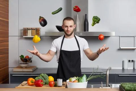 Man in the kitchen juggling with vegetables Stock Photos