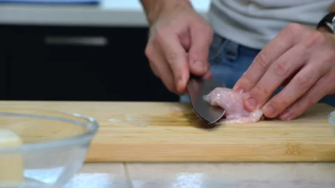 Man in Kitchen. Knife Cuts Chicken Fillet in Half. Slicing Meat on Wooden Board Stock Footage 147167531