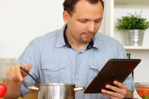 Man in kitchen looking at recipe on electronic tab during cooking Stock Footage 8983580