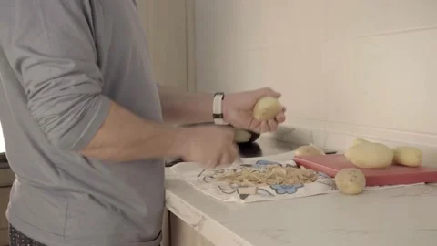 Man in kitchen peeling potatoes on a hob 스톡 동영상 238359846