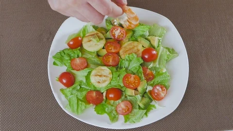 A man in the kitchen prepares a salad of avocado, zucchini and cherry tomatoes Video stock 101818532