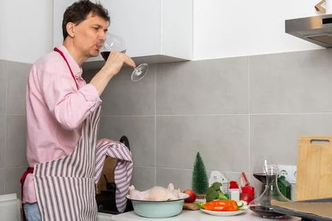 A man is in a kitchen preparing a pre-Christmas dinner. He is focused on baki Stock Photos