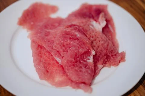 A man in the kitchen preparing red meat. A piece of meat, seasoned with pepper Stock Photos