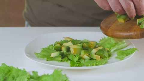 A man in the kitchen is preparing a salad of avocado and cherry tomatoes. Stock Footage 101818011