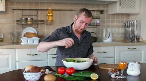 Man in the kitchen preparing a salad, it pours lemon juice Stock Footage 59005600
