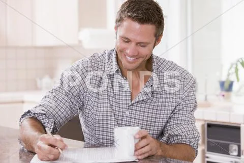 Man in kitchen reading newspaper and smiling Stock Photos