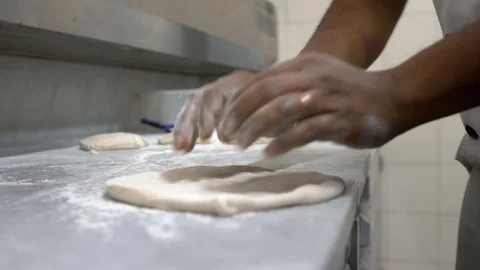 Man in kitchen rolls dough, throws, distributes flour under it and turns it over Stock Footage 104618273