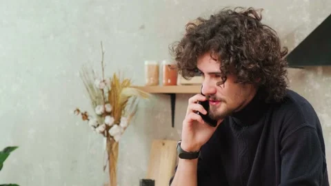 Man on kitchen is smiling, drinking coffee and talking on a smart phone. Stock Footage 151906631