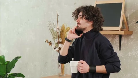 Man on kitchen is smiling, drinking coffee and talking on a smart phone. Stock Footage 152831709