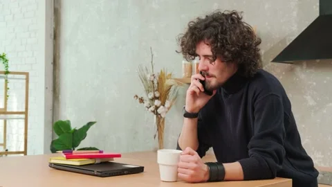Man on kitchen is smiling, drinking coffee and talking on a smart phone. Stock Footage 152978980