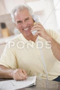 Man in kitchen on telephone smiling Stock Photos
