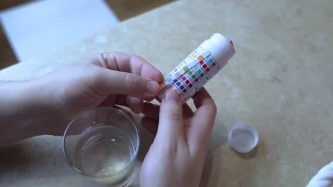 A man in the kitchen tests tap water quality with a test strip. Home testing for Stock Footage 327855819