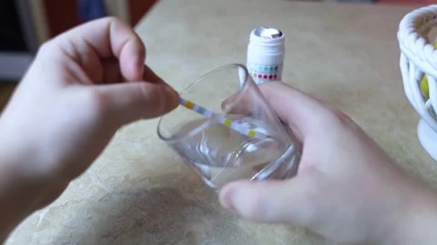 A man in the kitchen tests tap water quality with a test strip. Home testing for Stock Footage 327855820