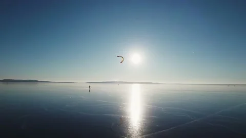 A man with a kite rides on the frozen surface of the river on skates. Extreme Stock Footage 229868533