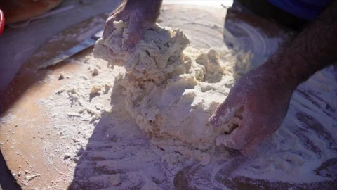 Man kneading dough in flour on large board with bare hands, close up of hands fr Vídeos de archivo 312977592