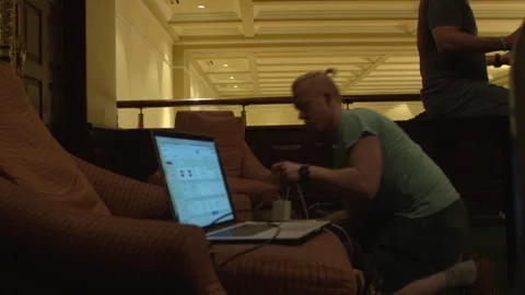 Man Kneeling and Working on Laptop in Hotel Lobby 스톡 동영상 342563679