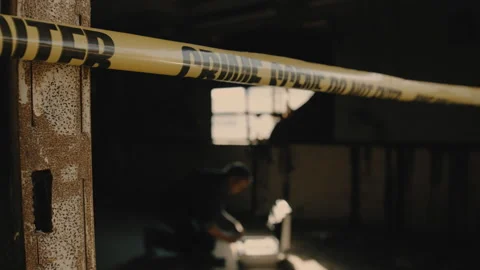Man kneeling by briefcase in room behind crime scene tape Stock Footage 275709447