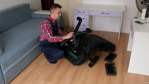 A man is kneeling down to fix a broken chair Stock Footage 274064529