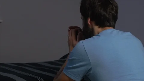A man kneeling by his bed praying through an open bedroom door. ZOOM OUT, Stock Footage 100334743