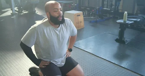Man kneeling on mat after finishing hex dumbbell set, breathing and recovering Stock Footage 336059366