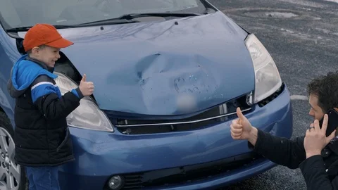 Man kneels down in front of wrecked car on the phone and gets thumbs Stock Footage 104701276