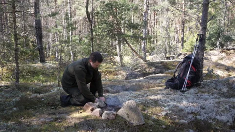 Man kneels forest clearing, arranging stones Vidéo 333403029