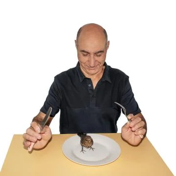 A man with a knife and fork looks at a live bird in a plate. Stock Photos