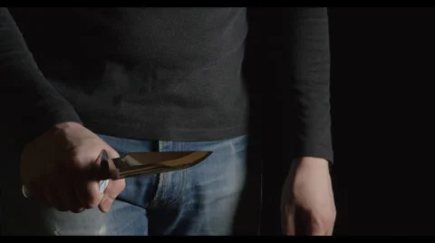 Man with a knife comes in the frame from a dark and moves on Stock Footage 62588029