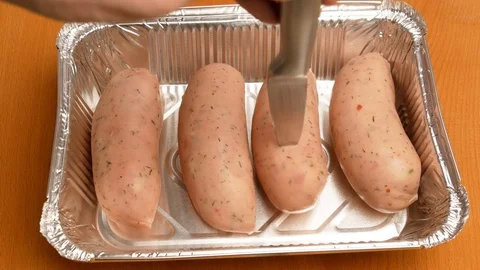 Man with a knife pierces sausage before baking in the oven. Stock Footage 107730833