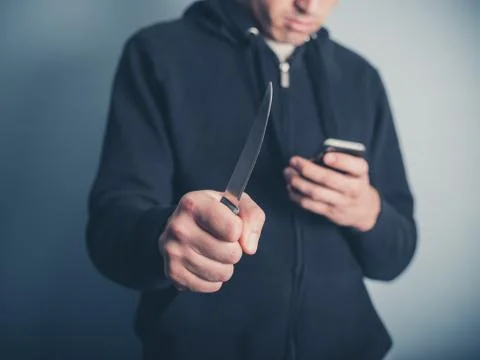 Man with knife using smartphone Photos