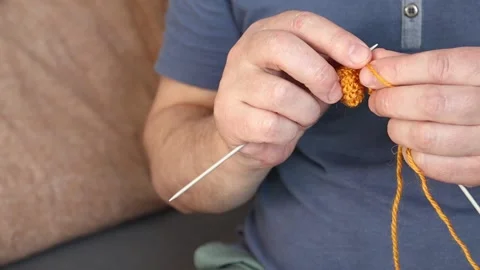 Man knitting a scarf with orange threads. Handmade at home Video stock 150477662