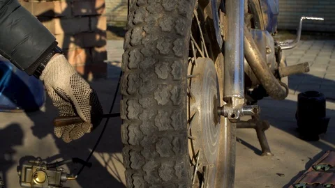 A man knocks out a fitting that holds the wheel. Repair of a motorcycle Stock Footage 123583426