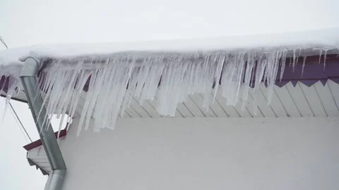 Man knocks sharp icicles off roof eaves Stock Footage 337014757