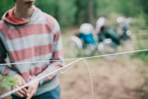 Man with knotted rope in forest. Setting up campsite. Stock Photos