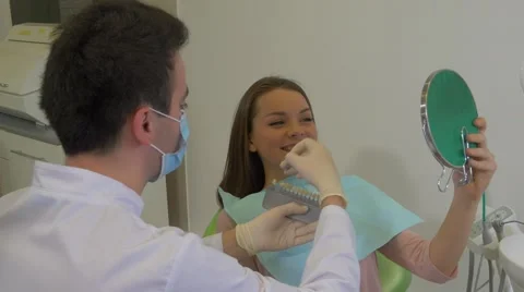 Man in Lab Coat Dentist Trying a New Teeth Color For a Young Woman Doctor in Stock Footage 60981445