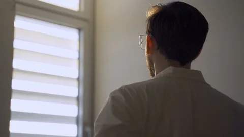 Man with lab coat stands next to lab window during sunset or sunrise Stock Footage 112610720