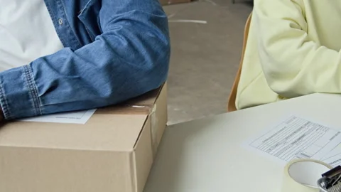 Man Labeling and Scanning Cardboard Box in Warehouse Stock Footage 337306079