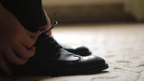 The man laces and tie his shoelaces on black shoes Vídeo Stock 76841925