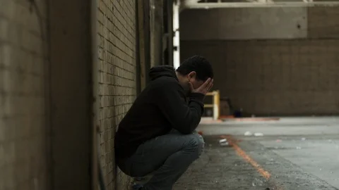 Man lamenting life while sitting in a burnt out warehouse Stock Footage 88051728