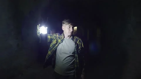 A man with a lantern in the dungeon. Goes a dark tunnel and holds a kaganets Stock Footage 234591935
