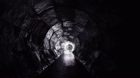 A man with a lantern walks in an underground round concrete rain collector.	 Stock Footage 130351530