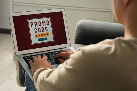 Man with laptop activating promo code while doing online shopping indoors, .. Fotos Stock