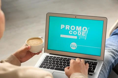 Man with laptop activating promo code while doing online shopping indoors, .. Foto stock