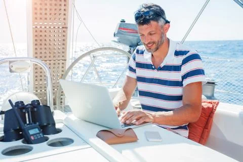 Man with laptop computer on sailboat 写真素材